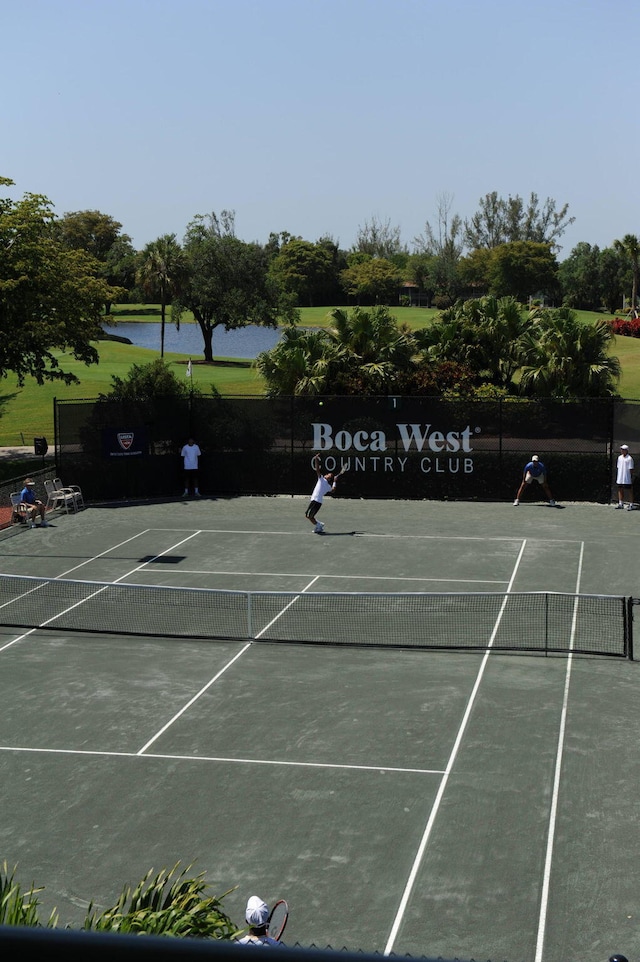 view of sport court featuring fence and a water view