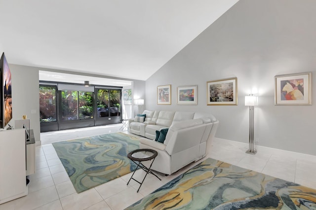 tiled living area featuring high vaulted ceiling and baseboards