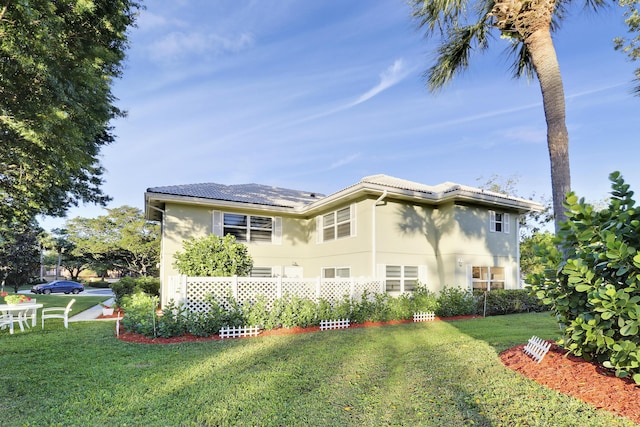 back of property with stucco siding, a lawn, and a tile roof