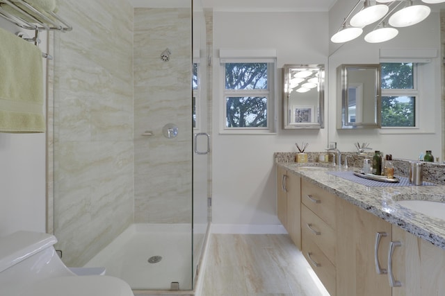 bathroom featuring baseboards, double vanity, a sink, a shower stall, and toilet