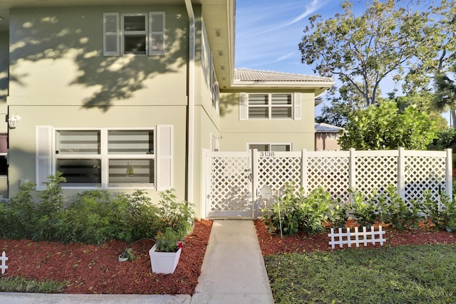 view of side of home with stucco siding and fence