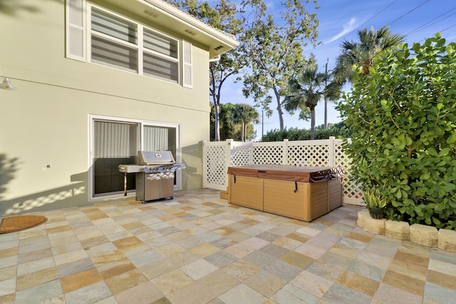 view of patio / terrace with grilling area, fence, and a hot tub