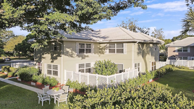 exterior space featuring stucco siding, a tile roof, a yard, and fence