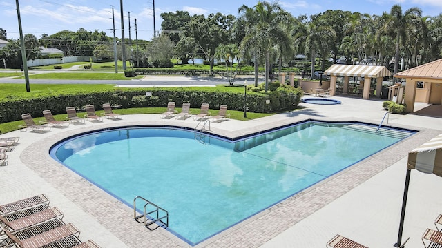 pool with a patio area and a hot tub