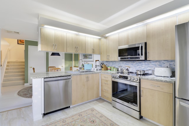 kitchen featuring visible vents, light brown cabinets, appliances with stainless steel finishes, a peninsula, and a sink