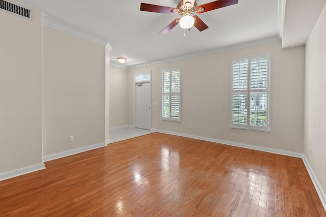 spare room featuring visible vents, light wood-style floors, ornamental molding, and a ceiling fan