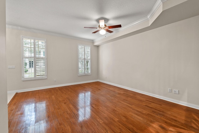 empty room with a ceiling fan, baseboards, ornamental molding, hardwood / wood-style flooring, and a textured ceiling