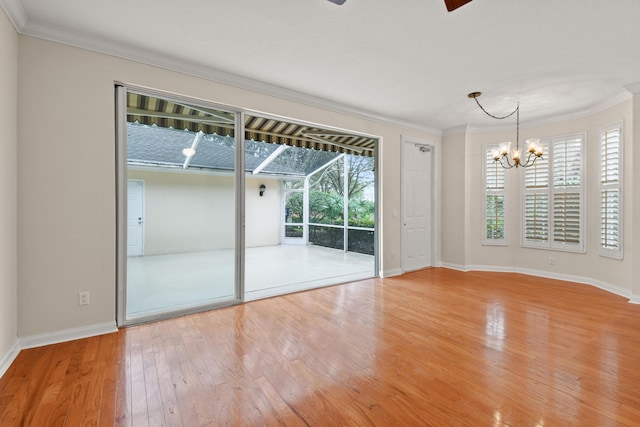 spare room featuring ceiling fan with notable chandelier, crown molding, baseboards, and wood-type flooring