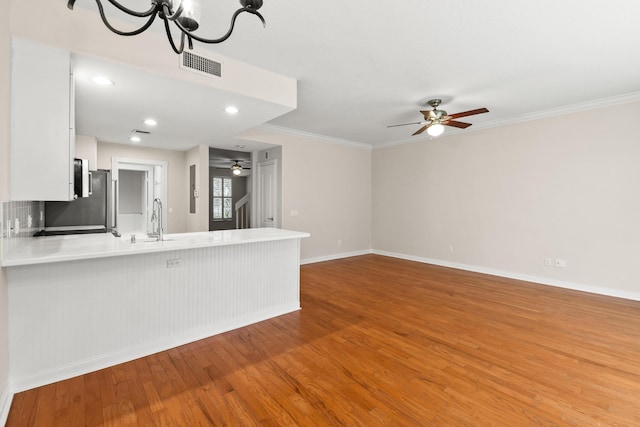 unfurnished living room with visible vents, a ceiling fan, wood finished floors, crown molding, and baseboards