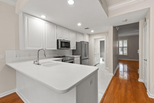 kitchen featuring visible vents, backsplash, white cabinets, stainless steel appliances, and a sink