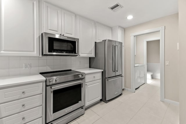 kitchen with visible vents, tasteful backsplash, white cabinetry, stainless steel appliances, and light countertops