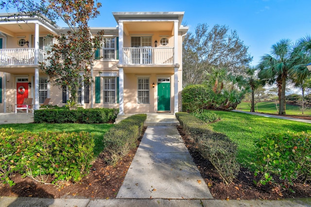 view of front of house with a front lawn, a balcony, and stucco siding