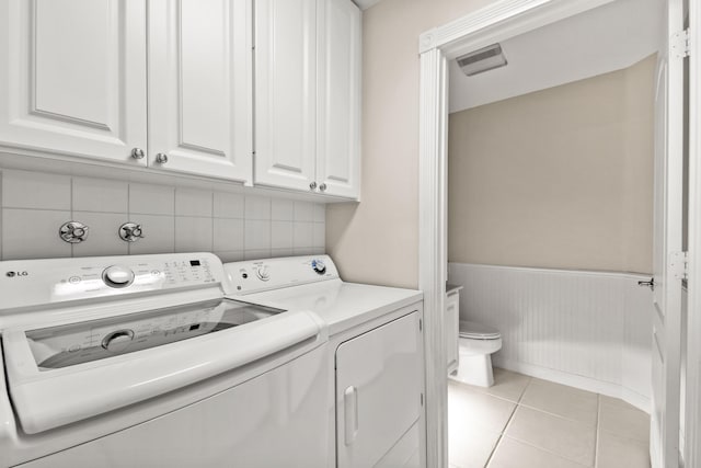 washroom with light tile patterned floors, separate washer and dryer, visible vents, and wainscoting