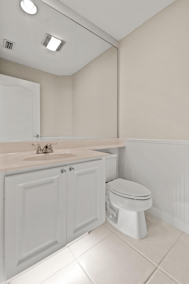 bathroom featuring visible vents, toilet, wainscoting, tile patterned flooring, and vanity