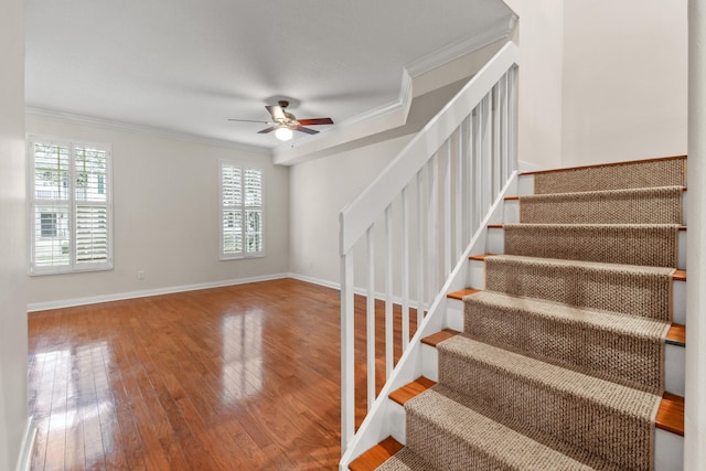 stairs featuring a ceiling fan, crown molding, baseboards, and hardwood / wood-style floors