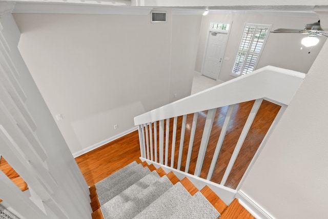 stairs featuring visible vents, baseboards, wood finished floors, and a ceiling fan