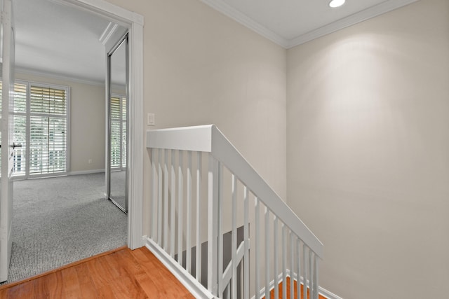 stairs featuring carpet floors, crown molding, baseboards, and wood finished floors