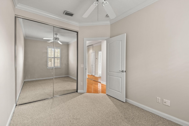 unfurnished bedroom featuring visible vents, ceiling fan, ornamental molding, carpet flooring, and a closet