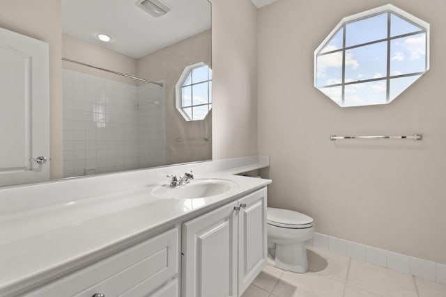 bathroom featuring vanity, baseboards, tile patterned flooring, walk in shower, and toilet