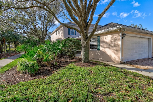 view of side of home featuring an attached garage, a lawn, and stucco siding