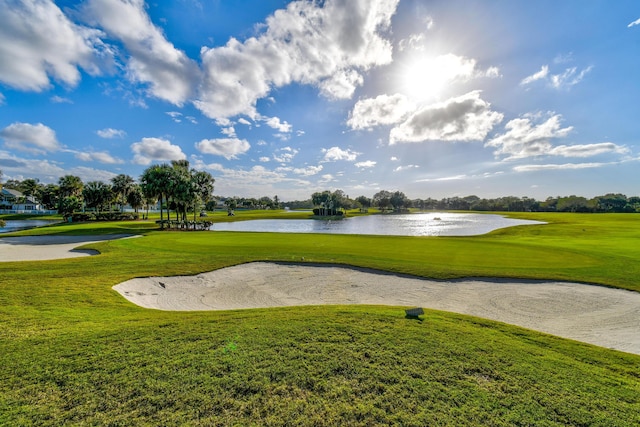 view of home's community with a water view, a lawn, and view of golf course