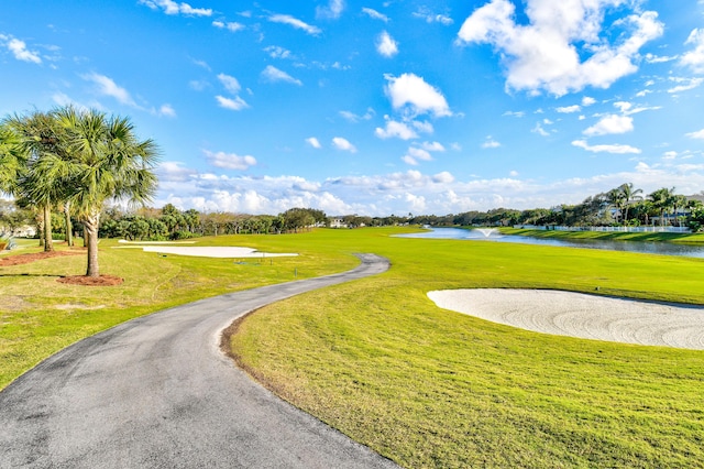 view of property's community with a yard, golf course view, and a water view