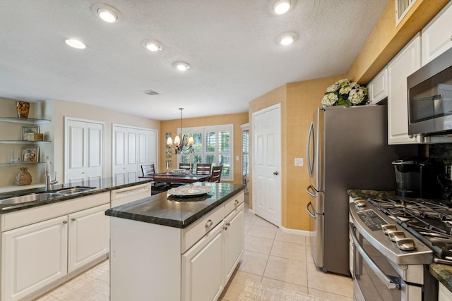 kitchen featuring an inviting chandelier, stainless steel appliances, a sink, white cabinets, and a center island