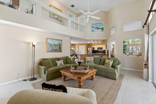 living area with light tile patterned flooring, baseboards, and ceiling fan