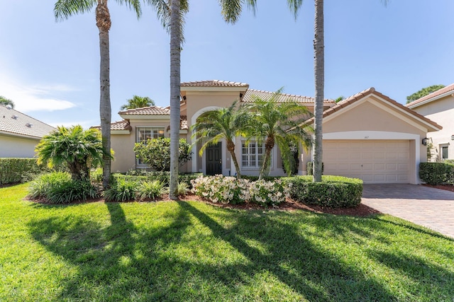 mediterranean / spanish-style home featuring stucco siding, decorative driveway, a front lawn, and a tile roof