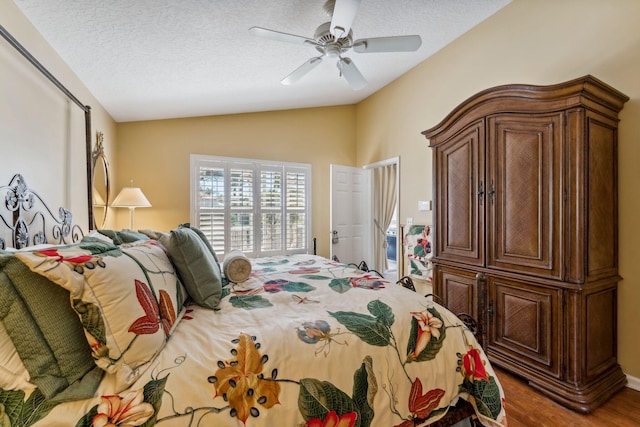 bedroom with ceiling fan, a textured ceiling, lofted ceiling, and wood finished floors