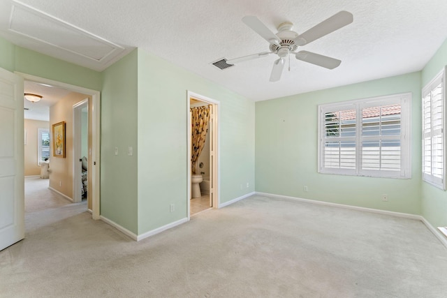 unfurnished bedroom with visible vents, a textured ceiling, attic access, and carpet flooring