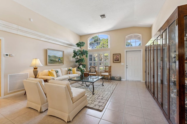 living area featuring visible vents, a textured ceiling, a high ceiling, light tile patterned flooring, and baseboards