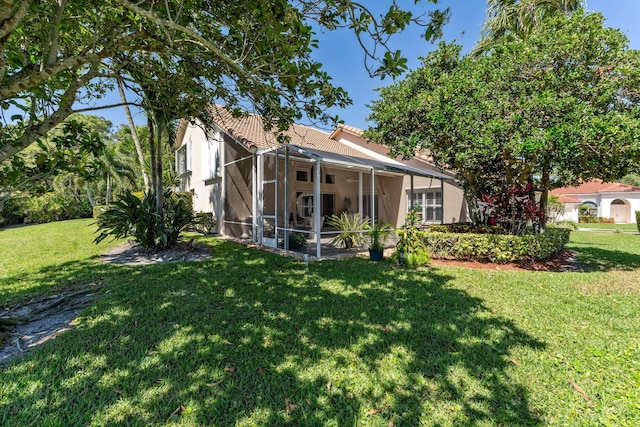 back of property featuring a lanai, stucco siding, a tiled roof, and a yard