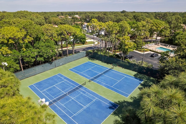 view of sport court featuring a view of trees and fence