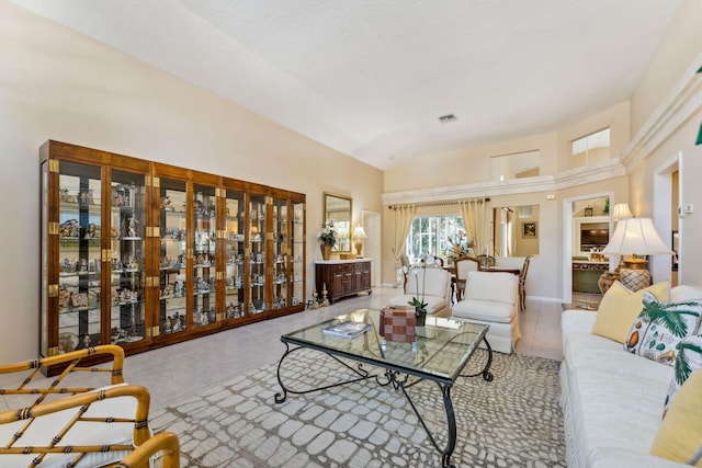 living area featuring tile patterned floors, visible vents, high vaulted ceiling, and baseboards