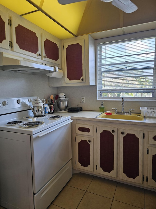 kitchen with under cabinet range hood, light countertops, light tile patterned floors, white electric range oven, and a sink