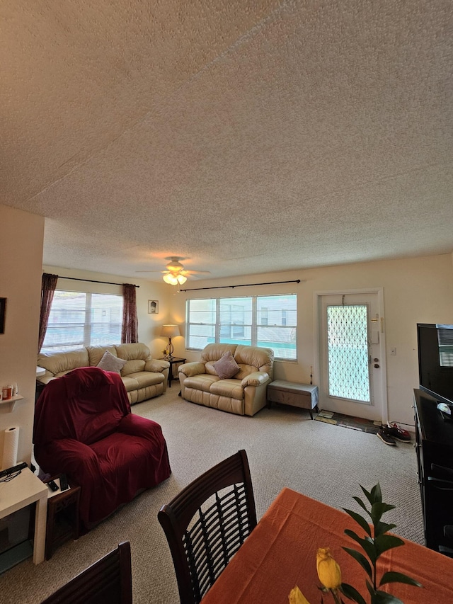 carpeted living area with a ceiling fan, a healthy amount of sunlight, and a textured ceiling