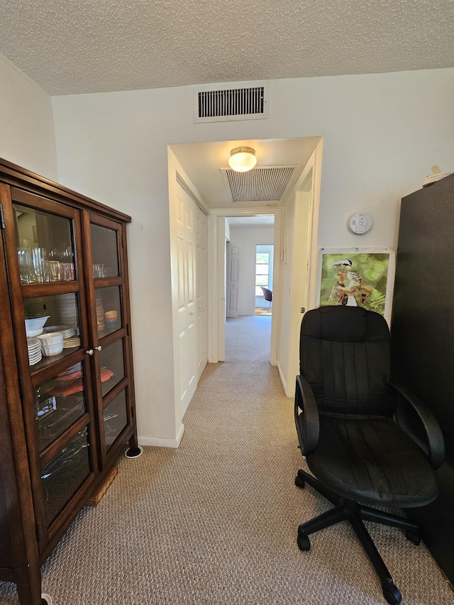 office space with visible vents, light carpet, and a textured ceiling