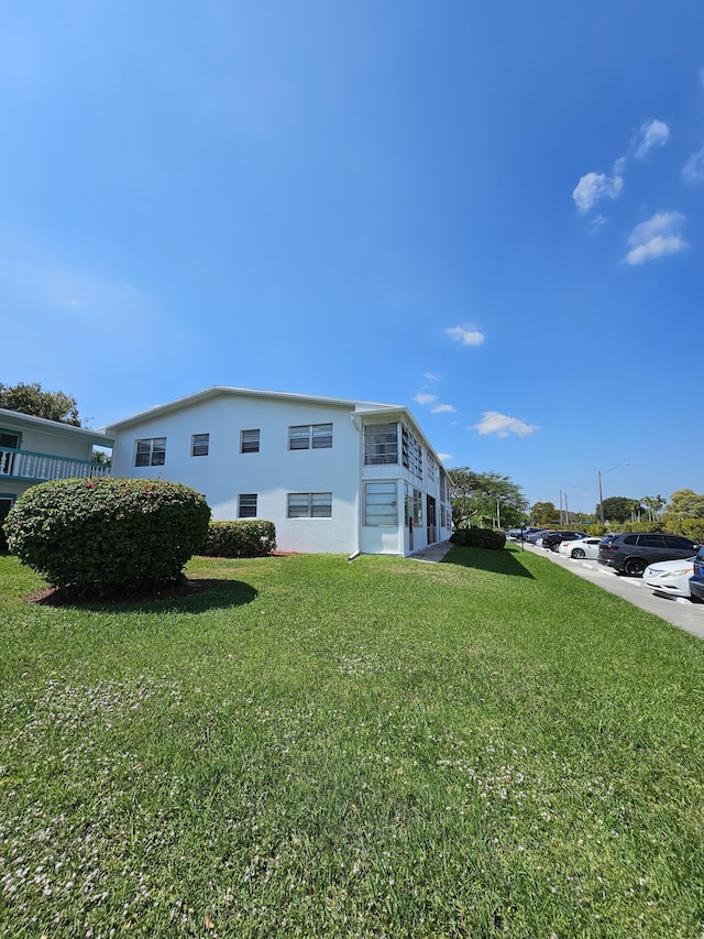 view of side of property featuring a lawn and stucco siding