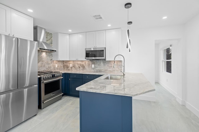 kitchen with a sink, backsplash, appliances with stainless steel finishes, a peninsula, and wall chimney range hood