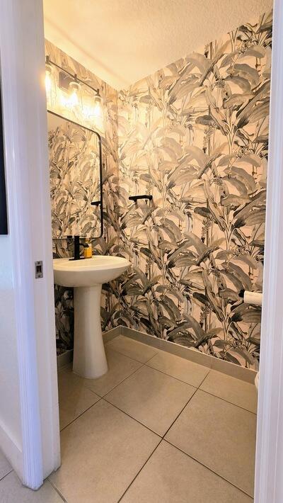 bathroom featuring wallpapered walls, tile patterned floors, and baseboards