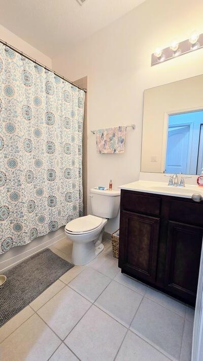 bathroom with tile patterned floors, curtained shower, toilet, and vanity