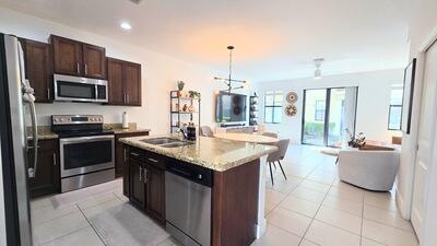 kitchen with a sink, open floor plan, stainless steel appliances, dark brown cabinetry, and light tile patterned floors