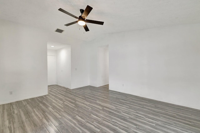 spare room with a ceiling fan, wood finished floors, and visible vents