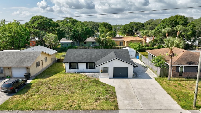 exterior space with a front yard, a residential view, a garage, fence, and concrete driveway