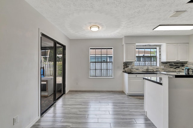 kitchen featuring white cabinets, backsplash, a sink, and light wood-type flooring