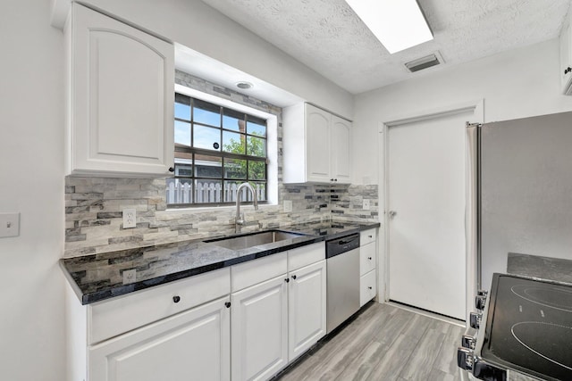 kitchen featuring stainless steel dishwasher, visible vents, light wood-type flooring, a textured ceiling, and a sink