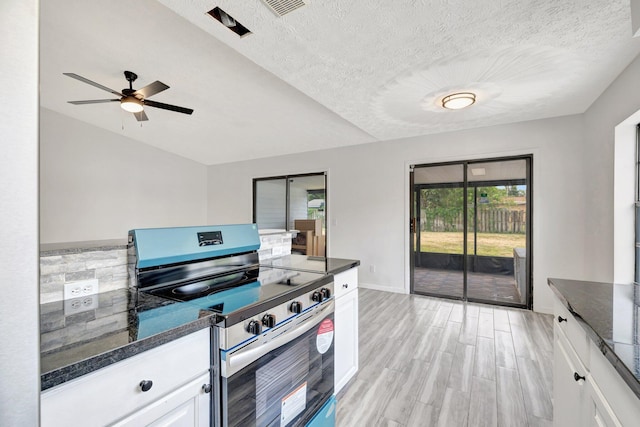 kitchen featuring white cabinets, stainless steel range with electric cooktop, ceiling fan, dark stone counters, and light wood-type flooring