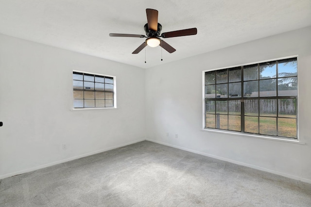 carpeted empty room with baseboards, plenty of natural light, and ceiling fan