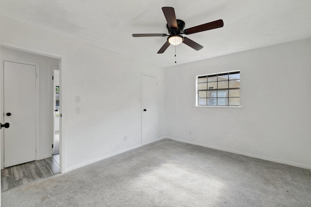 carpeted empty room featuring baseboards and a ceiling fan